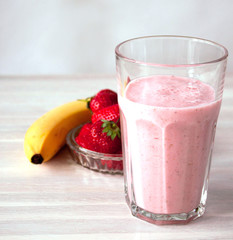 Strawberry milskhake glass, bowl strawberries, banana on white. Healthy eating breakfast concept