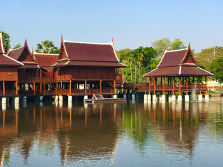 High roof Thai traditional wooden house  with reflection on water and blue sky background