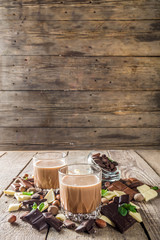 Sweet and strong alcohol drink. Chocolate liqueur with milk and dark chocolate pieces. Wooden background copy space