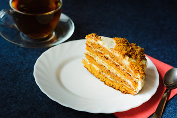 piece of cake on a white plate with cup of tea 