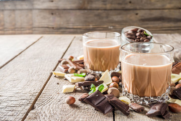 Sweet and strong alcohol drink. Chocolate liqueur with milk and dark chocolate pieces. Wooden background copy space