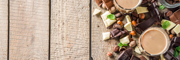 Sweet and strong alcohol drink. Chocolate liqueur with milk and dark chocolate pieces. Wooden background copy space