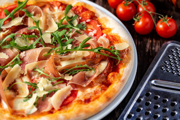 Close up of a deliciously flavored pizza with grater and cherry tomatoes in the background