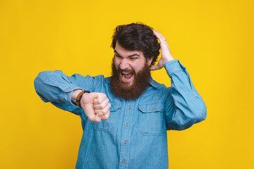 Amazed man looking shocked at smartwatch over yellow background
