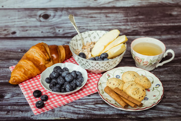Petit déjeuner sain thé avec croissant biscuits cannelle muesli pommes et myrtilles