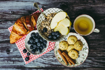 Petit déjeuner sain thé avec croissant biscuits cannelle muesli pommes et myrtilles
