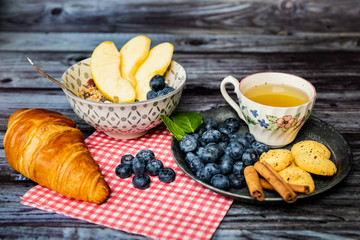Petit déjeuner sain thé avec croissant biscuits cannelle muesli pommes et myrtilles