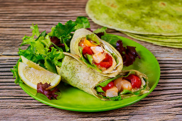 Wrap with grilled chicken and vegetable on plate with green salad and lemon.