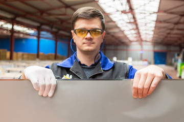 A man shows how to keep sharp sheets of tin, in protective gloves and without. Focus on hands