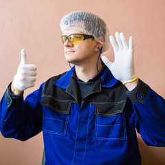 A man in special clothes in white gloves, a hat, protective glasses, earplugs in a food processing plant. Requirements for clothing in food production.