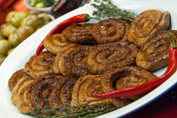 Homemade sausage, red pepper and rosemary on a white plate. Street food
