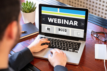Man working on a laptop with the word webinar on the computer screen