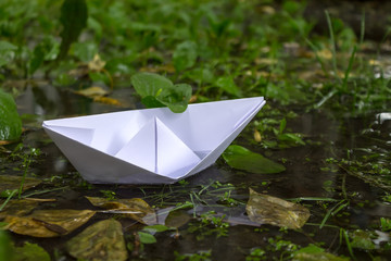 Origami in the form of a paper boat floating in the city puddles