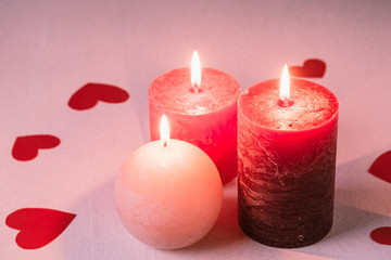 Obraz na płótnie Canvas Three wax flame candlelight with paper red hearts valentines on white background, love dating, Valentine's day, selective focus
