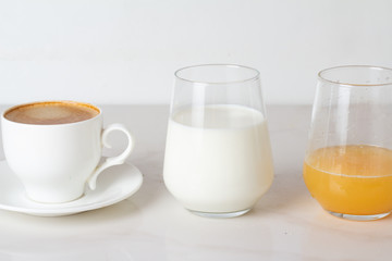 different drinks for breakfast: coffee, juice and milk on a white background