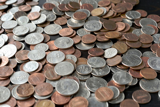 A pile of American cents on an old black wooden surface close-up. Money background