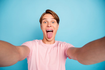 Close up photo of funny crazy expression guy relax rest on summer holidays grimace fool show tongue make selfie wear good looking outfit isolated over blue color background