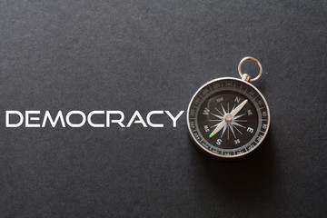 Democracy word written on black background with compass