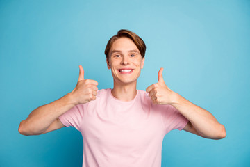Photo of nice young guy funny expression good mood raising thumb fingers up advising cool quality...