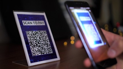 QR code cashless payment. Scan to pay system. Business or technology concept: young man using smartphone for scanning QR codes for payment a purchase or service