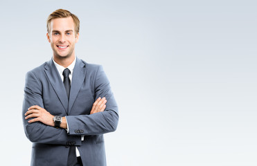 Portrait of happy smiling young businessman in grey confident suit, with copy space for some slogan...