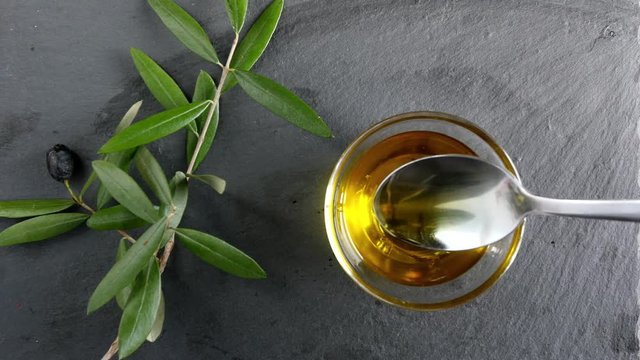 Extra Virgin oil. A tablespoon hold on the olive oil. Healthy food, genuine Italian ingredient, natural product, dark background.