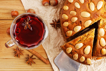 Closeup homemade cake with almonds and glass with mulled wine on a wooden table. Top view.