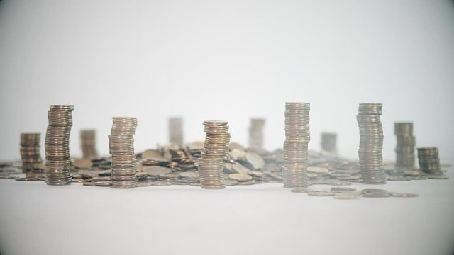 The concept of money. Columns of gold coins in the form of skyscrapers or Stonehenge. Close-up hands make up stacks of coins. Smoke. Garland.