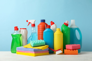 Bottles with detergent and cleaning supplies on blue background, space for text
