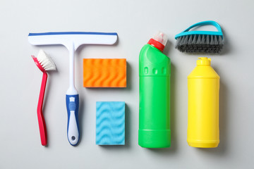 Flat lay with detergents and cleaning supplies on grey background, top view