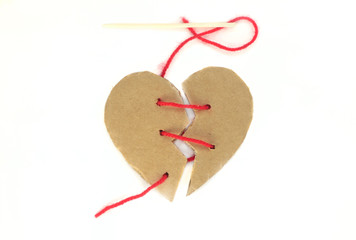 Broken cardboard heart on an isolated white background Two halves of the heart sewn together in red thread. The concept of a broken heart, unrequited love. Valentine's Day stock photo with empty space