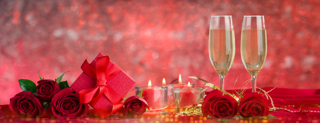 Champagne glasses, roses and candles on red drape