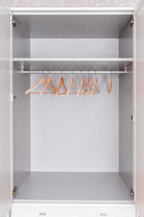 Home furniture. Spacious, bright and grey wardrobe from inside.Empty top drawer. Modern wooden clothes hangers hang on metal hook on rod