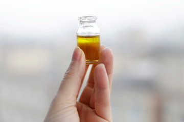 Woman hand holding bottle of Cannabis oil. CBD and THC oil at bright background. Medical support. Medicine alternative.  