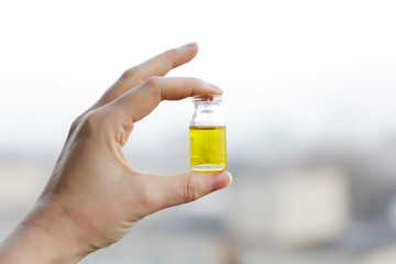 Woman hand holding bottle of Cannabis oil. CBD and THC oil at bright background. Medical support. Medicine alternative.  