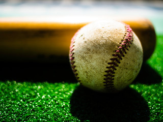 A baseball ball and Bat on Green Grass