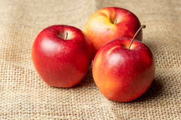 Apples. Three red ripe apples on burlap.