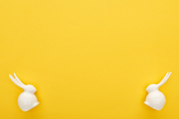 top view of white Easter bunnies on colorful yellow background