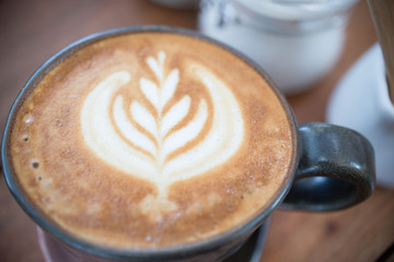 Coffee cup with Latte art on wooden table menu in coffee break time.Latte art froth design pattern is a method of preparing coffee.