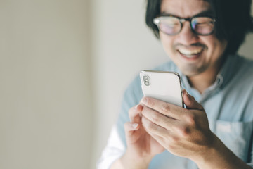 using cell phone.portrait young asian man wear eye glasses Smiling cheerful look screen texting chatting on mobile.contact connecting people freedom life style concept
