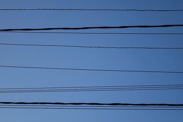 High-voltage wires against the blue sky, background