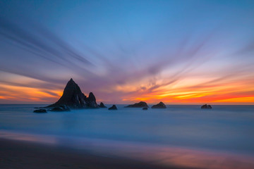 Fototapeta na wymiar A dramatic sky after the sunset with Shark Fin Rock at Martin's Beach, Half Moon Bay, in Northern California, USA