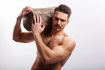 Athlete, sexy, brutal bearded man, with naked torso, holding a tree trunk on his shoulders, over...