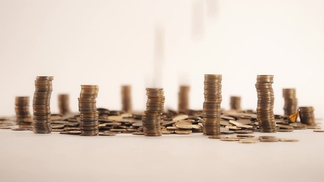 The concept of money. Columns of gold coins in the form of skyscrapers or Stonehenge. Close-up hands make up stacks of coins. Smoke. Garland.