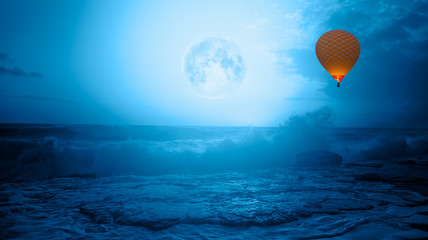 Hot air balloon flying over stormy sea in the background full moon at night" Elements of this image furnished by NASA"