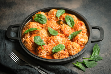 Meatballs in tomato sauce with bazil leaf in a frying pan on dark background. Top view.