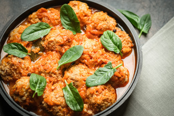 Meatballs in tomato sauce with bazil leaf in a frying pan on dark background. Top view.