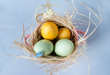 yellow, green Easter eggs on the hay in a pink plate on a blue background,