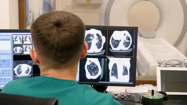 Radiologist looking at monitors with lungs activity results in control room. 4K