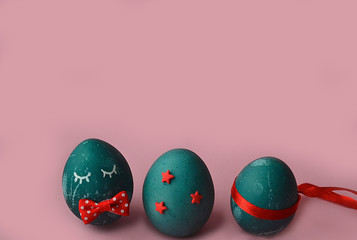 Creative Easter Funny blue egg with eyes and bow, easter bunny on pink background. Natural dye of...